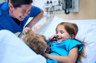 Enfermera y niña en hospital sonriente